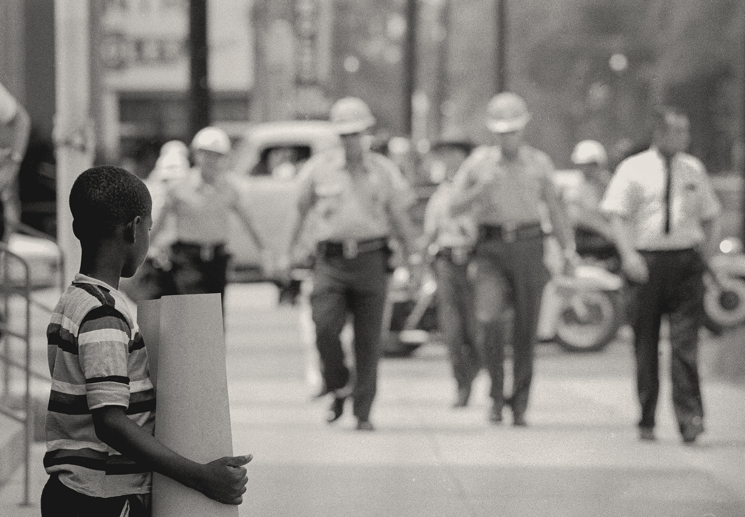 Deputies Approach Boy, Selma, Alabama, 1964. Photograph by Matt Herron. Sheriff's deputies coming to arrest a young boy holding a sign at a SNCC voter registration demonstration in front of the Dallas County courthouse. © 1976, Matt Herron / Photograph provided by TakeStock.