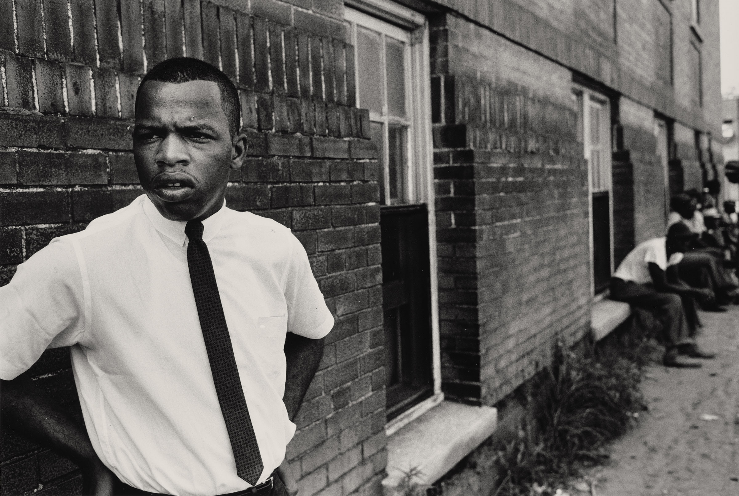 John Lewis, 1963. Photograph by Steve Schapiro. Portrait of John Lewis standing outside of a brick building in Clarksdale, Mississippi. Photograph in the collection of Miami University Art Museum, Oxford Ohio. Partial gift of the artist and partial purchase with contributions from the Kezur Endowment Fund (2019.23.12).