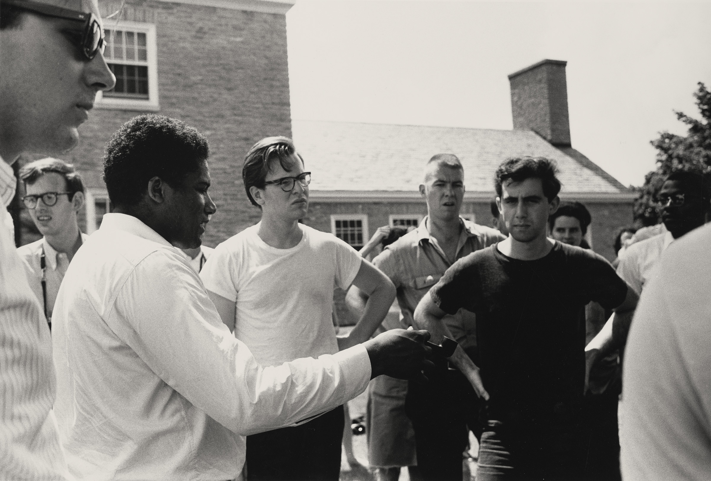 James Foreman and Andrew Goodman, June 1964. Photograph by Steve Schapiro. James Foreman leads a role playing activity to teach Freedom Summer volunteers how to respond nonviolently. Andrew Goodman, who will be killed in Mississippi that summer, is pictured in the black t-shirt. The photograph was taken during the Freedom Summer orientation session in Oxford, Ohio. Photograph in the collection of Miami University Art Museum, Oxford Ohio. Partial gift of the artist and partial purchase with contributions from the Kezur Endowment Fund (2019.23.16).