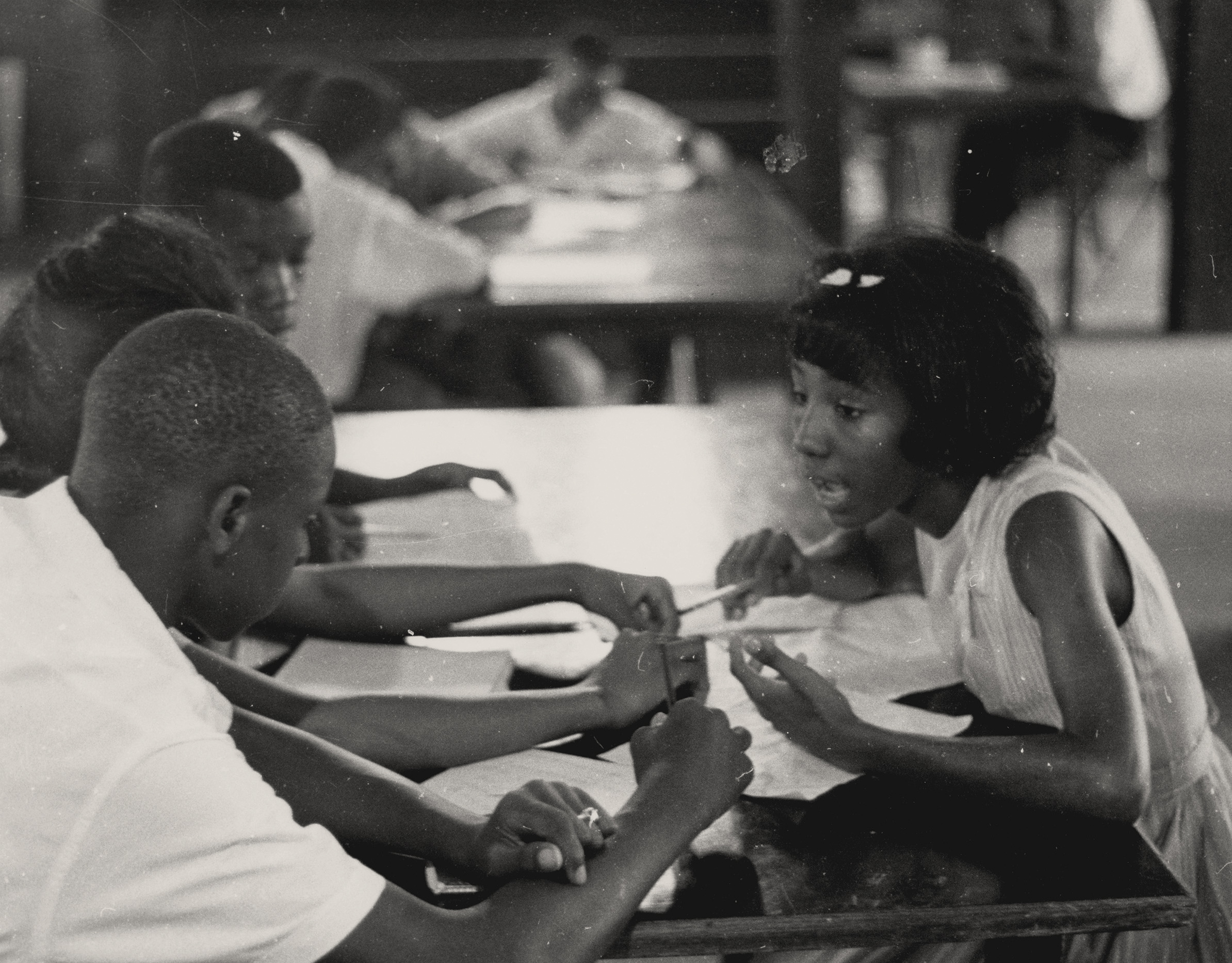 Freedom School Discussion, 1964. Photograph by Herbert Randall. Four Freedom School students engage in discussion while sitting at a table in the basement room of an African American church in Hattiesburg, Mississippi, during Freedom Summer. Alice Adams (right) is the only person identified in the photograph. M351 Herbert Randall Freedom Summer Photographs, Historical Manuscripts, The University of Southern Mississippi.
